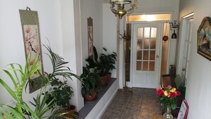 A hallway with potted plants, a wooden bench, a door with frosted glass panels, and a hanging light fixture. - Coach house cottage by sefton park, built in 1850.  Entire house ! (Liverpool)