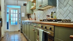 A kitchen with green cabinets, a tiled backsplash, and a wooden countertop. - Coach house cottage by sefton park, built in 1850.  Entire house ! (Liverpool)