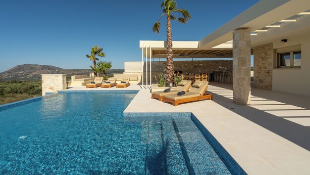 A modern pool area with clear blue water, sun loungers, and a palm tree. - Villa Athena (Apokoronas)