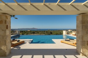 Una piscina al aire libre, sombrillas, sillones reclinables de piscina