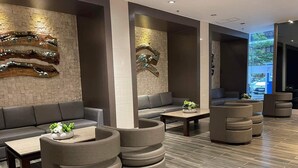 Ein stilvoller Lounge-Bereich mit Sofas, runden Sitzgelegenheiten und einer Steinwand mit dekorativen Elementen.