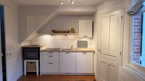 A compact kitchen with white cabinets, a wooden countertop, a built-in oven, and a small sink. - COTTAGE L'OUSTAL ideally located beach and seawall 100 meters away (Le Crotoy)