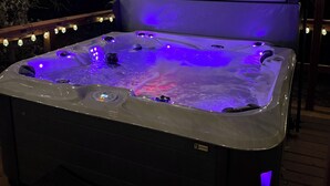 Een hottub met een houten terras en lichtslingers.