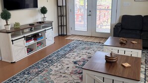 Een woonkamer met een televisie, bank, salontafel en een kamerkleed met dessin.