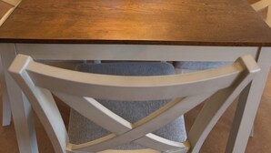 Een eettafel met stoelen, een vaas met planten en een keuken op de achtergrond.