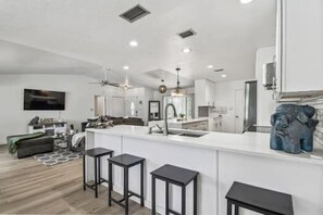 A modern kitchen with a central island, bar stools, and a pendant light. - Private Sarasota Oasis with heated pool & 10 minutes to Siesta Key (Sarasota)