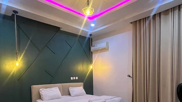 A modern bedroom with a large bed, a ceiling light fixture, and an air conditioning unit. - Smridu Hotel (Lagos)
