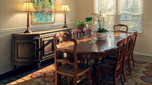 A dining room with a wooden table, six chairs, two lamps, a painting, a potted plant, and a window with blinds. - Masters Week Home Away from Home - 3BR Retreat Minutes from Augusta National (Augusta)