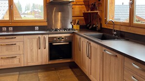 Une cuisine moderne avec des meubles en bois, une hotte en acier inoxydable et une grande fenêtre.
