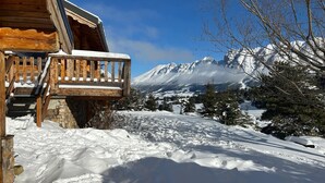 Une cabane en bois dotée d’un balcon donnant sur un paysage enneigé et des montagnes.