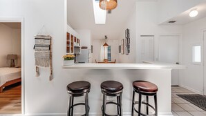 A modern kitchen with a white countertop, three stools, and a hanging light fixture. - Stylish Retreat Near Beaches & Attractions - Private, Clean, Comfortable (Jacksonville)