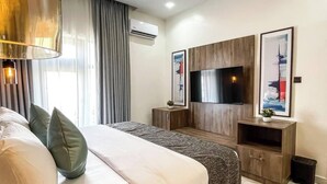 A modern hotel room with a large bed, a TV, and a wooden cabinet. - Adna Hotel (Lagos)