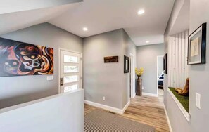 A hallway with a modern design, featuring a door, a framed artwork, and a decorative vase with flowers. - Gorgeous 4-bedroom house in Sedalia perfect for your getaway (Sedalia)