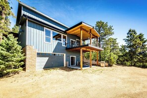 A modern two-story house with a large garage, a covered porch, and a view of a forested area. - Gorgeous 4-bedroom house in Sedalia perfect for your getaway (Sedalia)