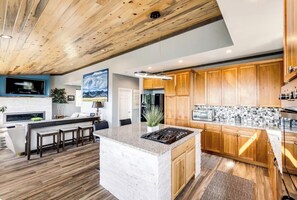 A modern kitchen with wooden cabinets, a central island, and a stone countertop. - Gorgeous 4-bedroom house in Sedalia perfect for your getaway (Sedalia)