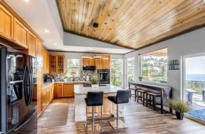 A modern kitchen with wooden cabinets, a central island, and a view of the outdoors. - Gorgeous 4-bedroom house in Sedalia perfect for your getaway (Sedalia)