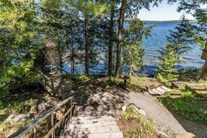 Un escalier en bois menant à une jetée au bord d’un lac, entouré d’arbres.