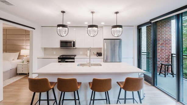 Una cocina moderna con una isla central, taburetes de bar e iluminación colgante.