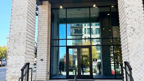 La entrada al Edificio 500 con un frente de vidrio transparente, revestimiento de ladrillo y una franja amarilla de seguridad que conduce a la entrada.