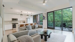 Una sala de estar moderna con sofá, mesa de centro y vistas a un balcón con mobiliario exterior.