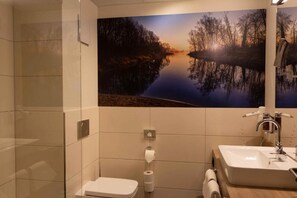 Une salle de bain avec des toilettes, un lavabo et un grand miroir.