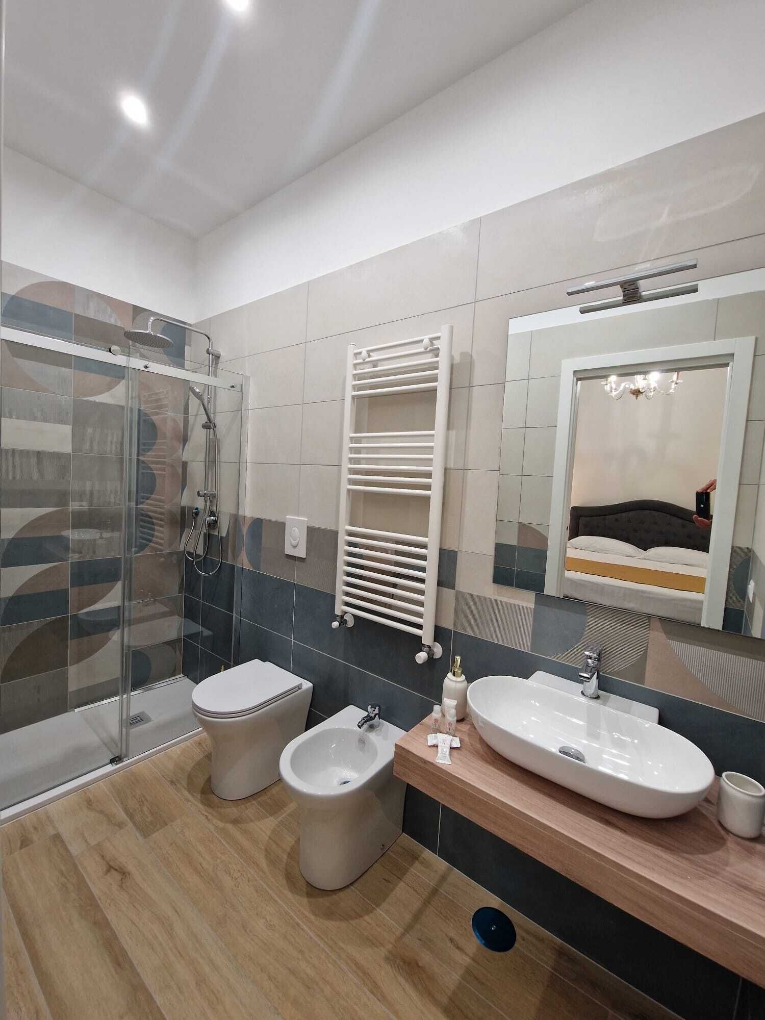 Un baño moderno con cabina de ducha de vidrio, inodoro, bidé y tocador con lavamanos y espejo.