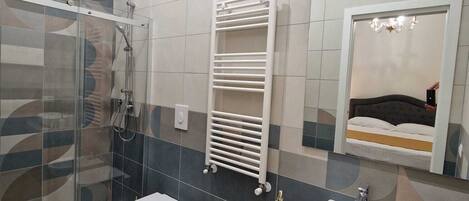 Un baño moderno con cabina de ducha de vidrio, inodoro, bidé y tocador con lavamanos y espejo.