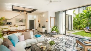 A modern living room with a sofa, coffee table, and a dining area. - Luxury Villa Near Beach with Pvt Pool & Garden (Anjuna)