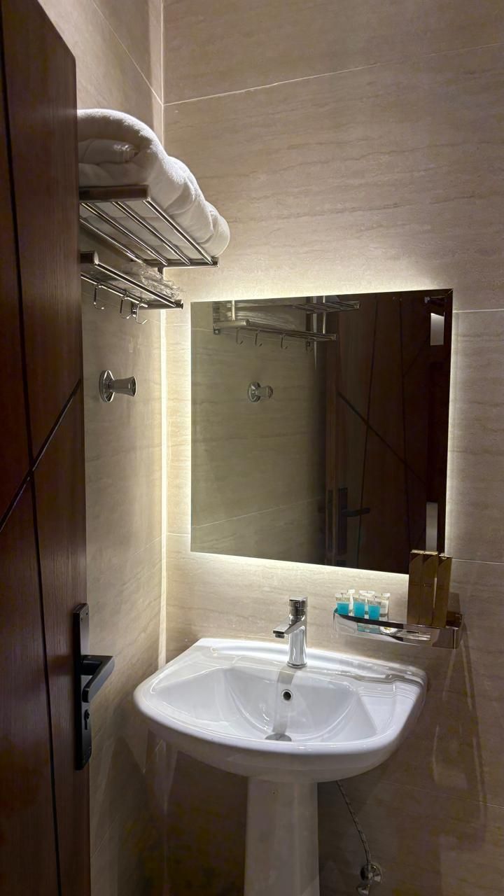 Une salle de bain moderne avec un lavabo blanc, un miroir et un porte-serviettes.