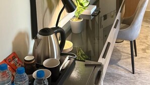 Una cocina moderna con televisión de pantalla plana, cafetera, hervidor y botellas de agua sobre la encimera.
