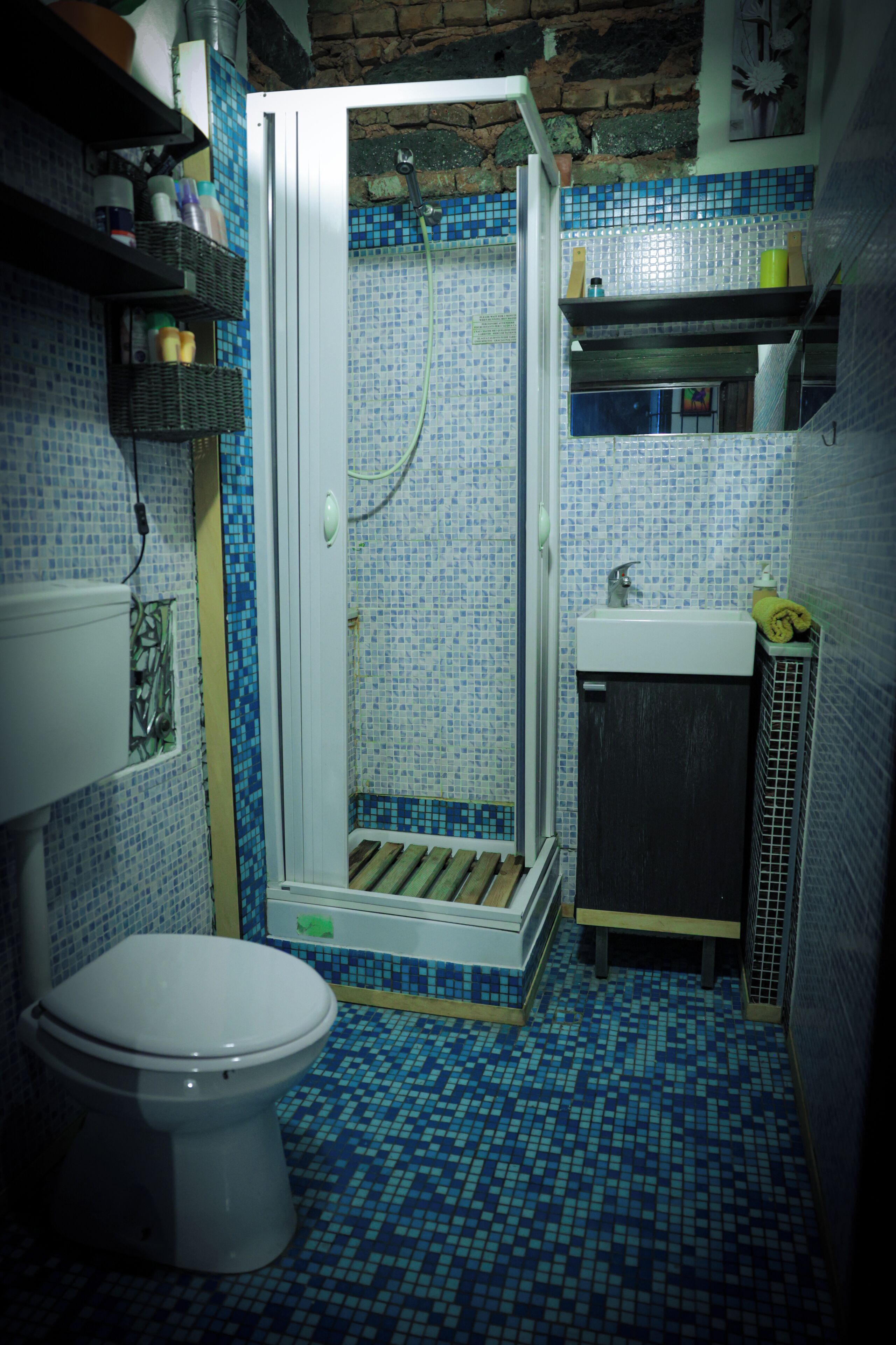 A bathroom with a shower, toilet, sink, and tiled floor.