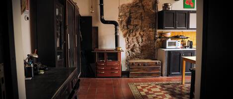 A kitchen with a stone wall, wooden cabinets, and a tiled floor.