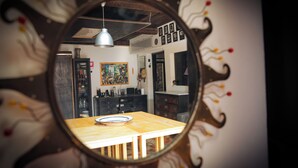 Ein Essbereich mit Holztisch und Stühlen, ein Spiegel der den Raum widerspiegelt und einer Deckenleuchte.