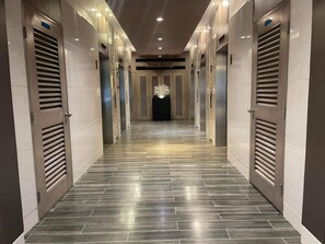 A hallway with a modern design, featuring a patterned floor and metallic doors with louvered panels. - Shore residences 18C1 MOA 1BR with balcony pool view By darpm (Pasay City)