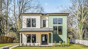 Ein zweistöckiges Haus mit einer Veranda, einer separaten Garage und einem umzäunten Garten.