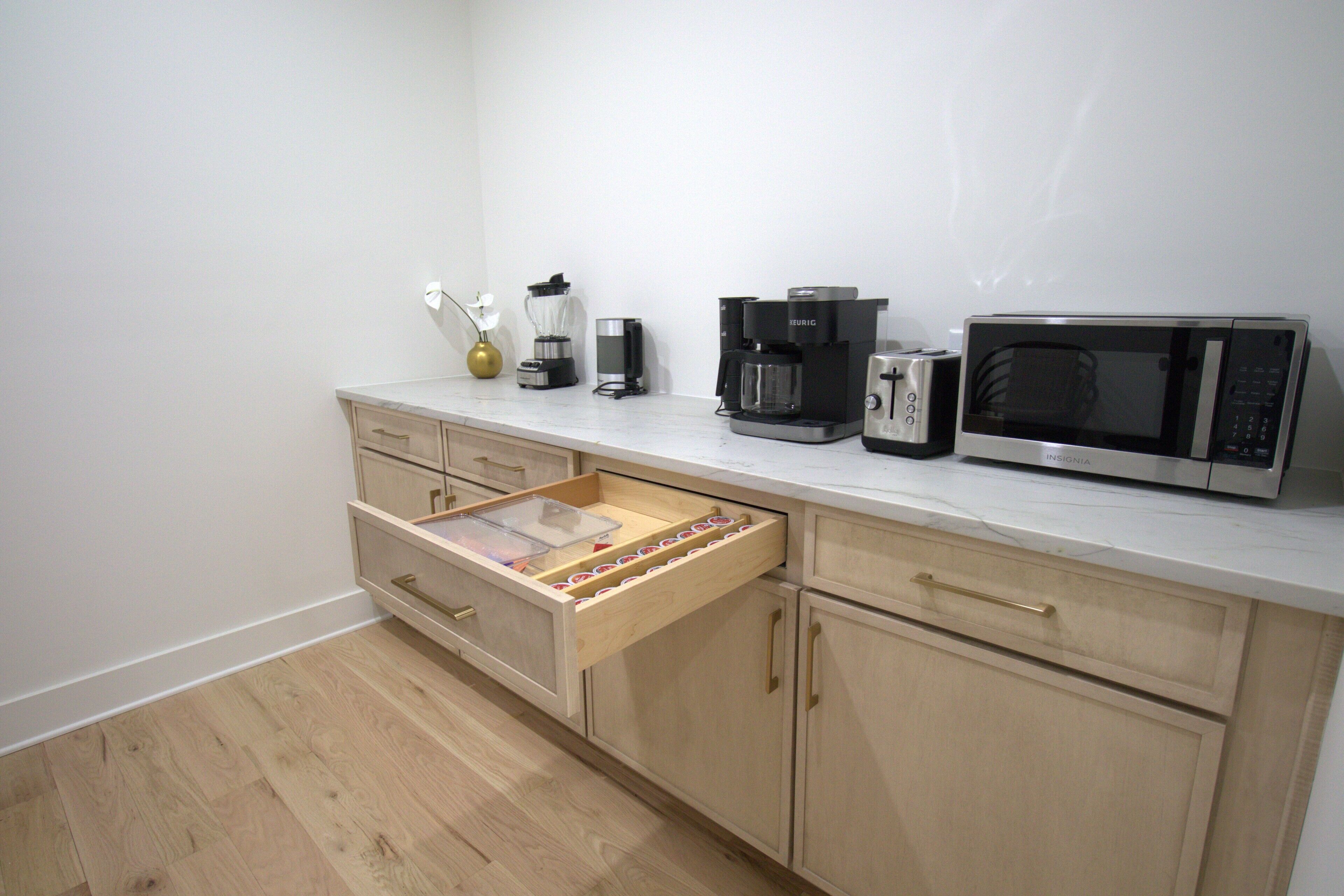 Eine Küche mit Holzschränken, einer Arbeitsplatte, einer Kaffeemaschine, einem Toaster und einer Mikrowelle.