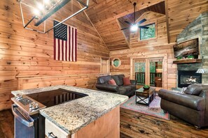 A log cabin interior with a kitchen island, a fireplace, a couch, and a TV. - Fun and Luxury: Game Room, Hot Tub, Pool Access (Sevierville)