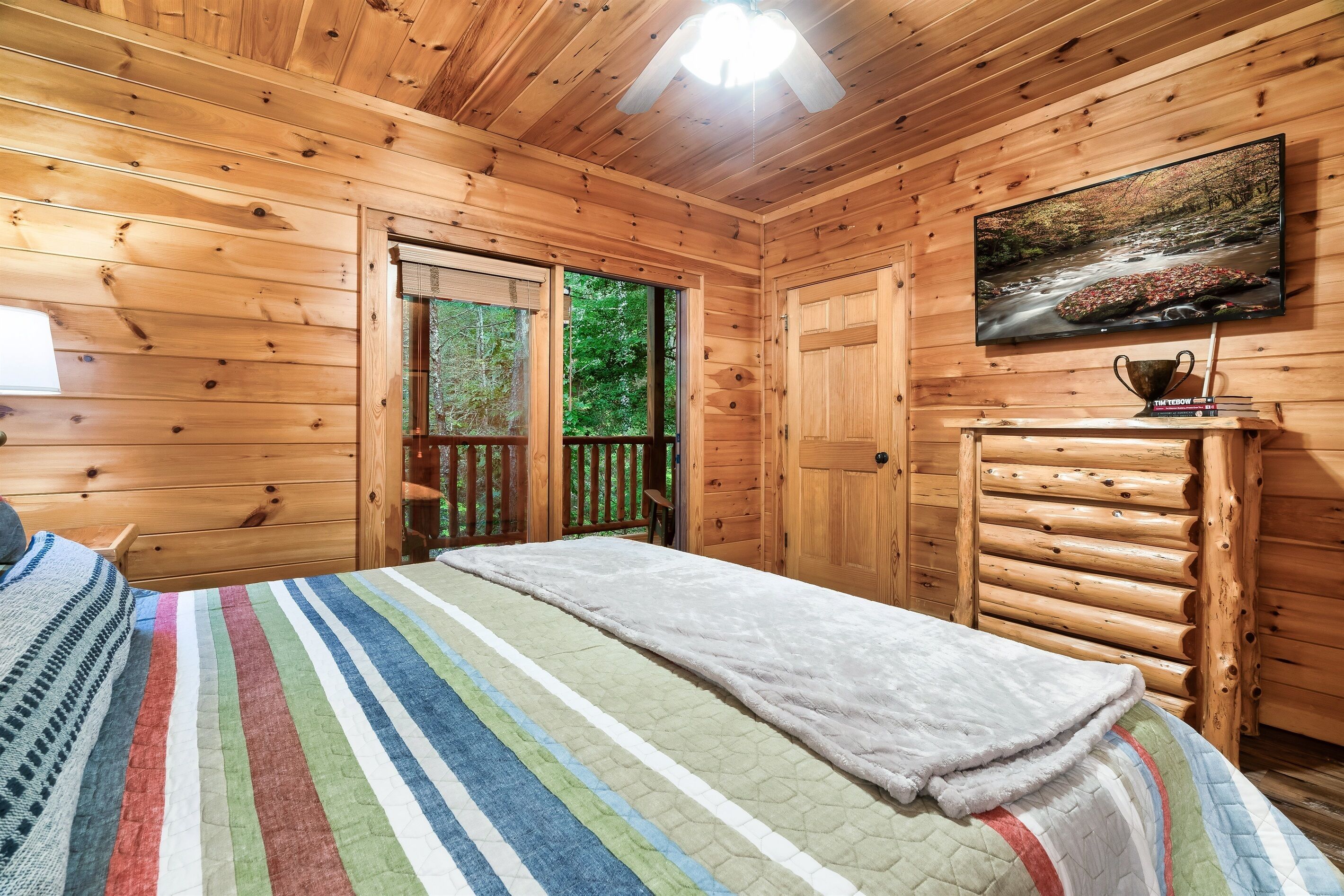 Een slaapkamer in een houten chalet met een bed, een televisie en een raam.