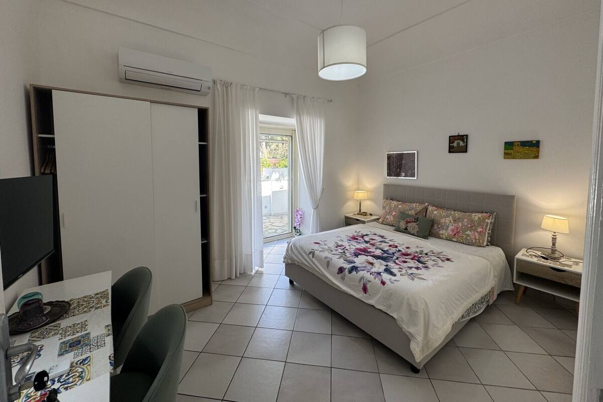 A bedroom with a bed, two bedside tables with lamps, a wardrobe, and a television.
