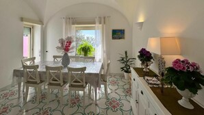 A dining area with a table and chairs, a potted plant, and a lamp. - Villa Azul (Anacapri)