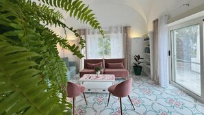 A living room with a sofa, coffee table, and chairs, a large window, and a plant. - Villa Azul (Anacapri)