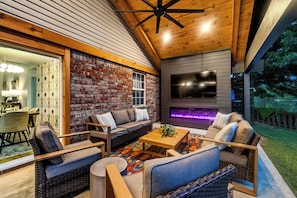 An outdoor living area with a brick wall, a fireplace, and a TV mounted on the wall. - Lakefront 4BR on Lake Hamilton, Dock, Hot Tub, Game Room, Sleeps 10 (Hot Springs)