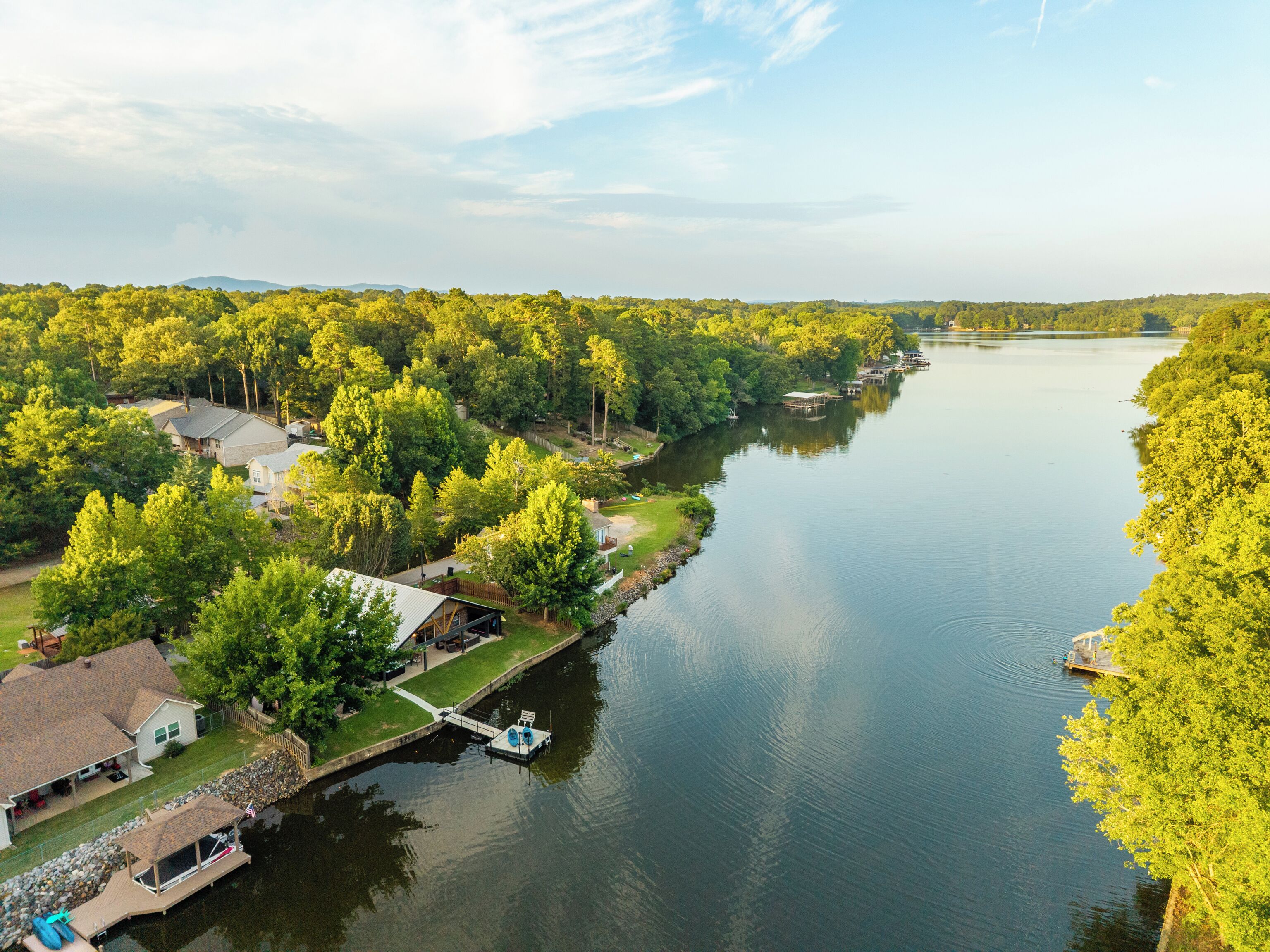 Propiedad frente al río con muelle, casas y abundante vegetación.