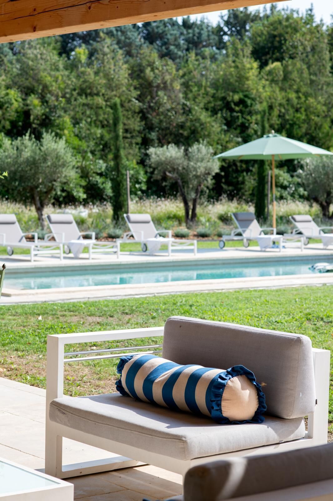 A poolside lounge area with a bench and a striped cushion.