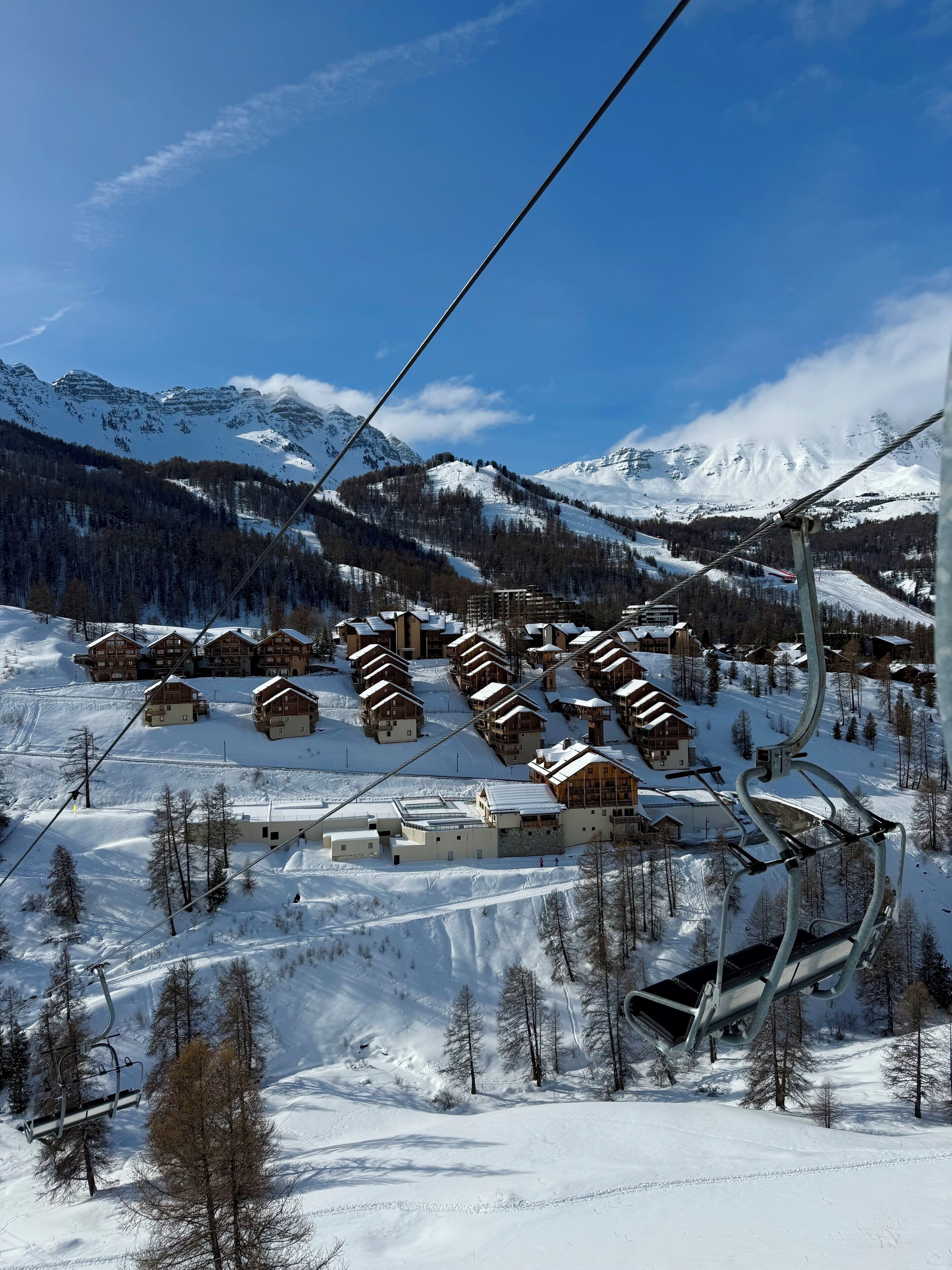 A ski lift with cabins and buildings in a snowy mountainous area.