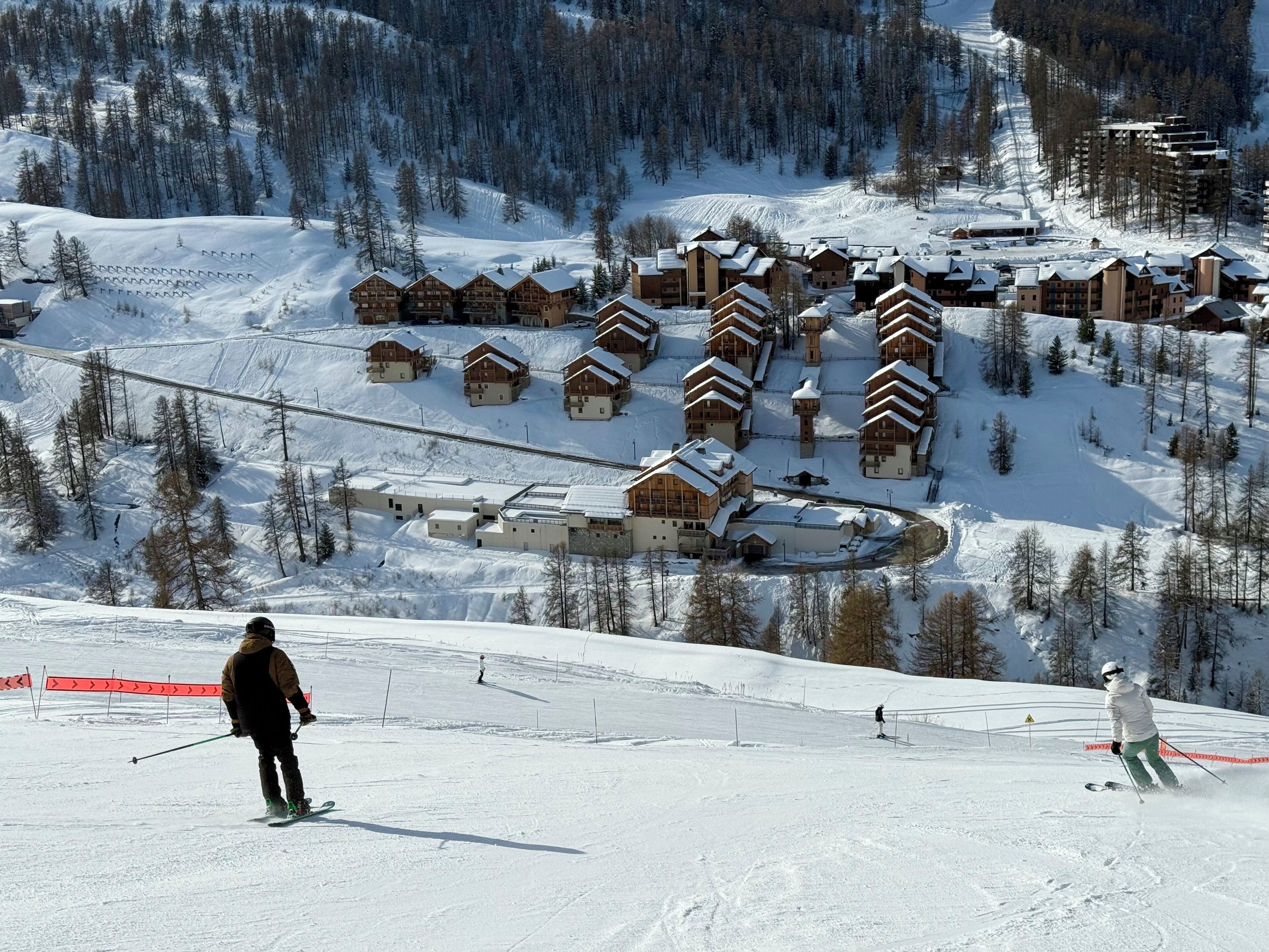A ski resort with multiple wooden lodges, ski slopes, and a snow-covered landscape.
