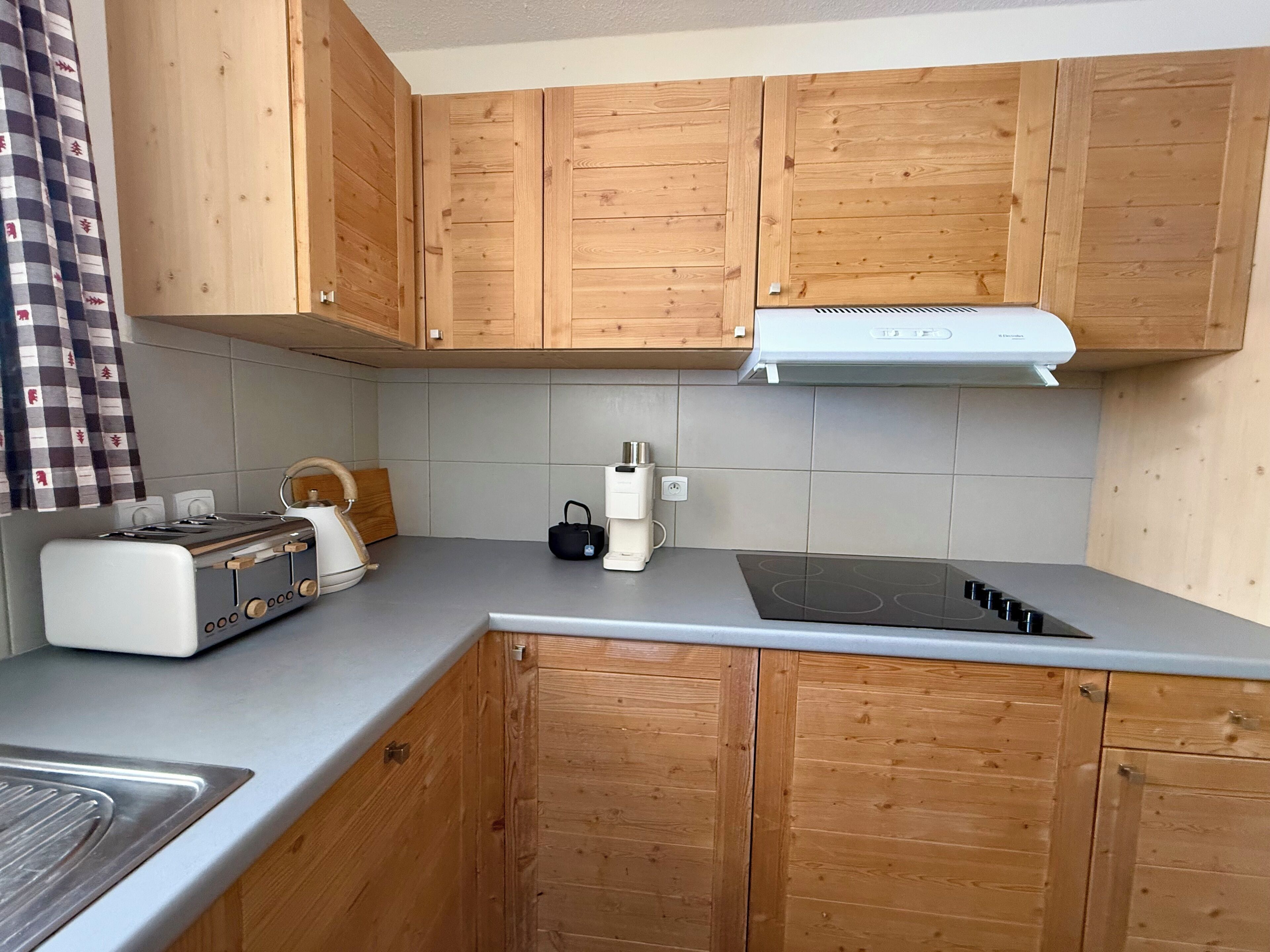 Eine Küche mit Holzschränken, einem eingebauten Herd, einem Wasserkocher und einem Toaster.