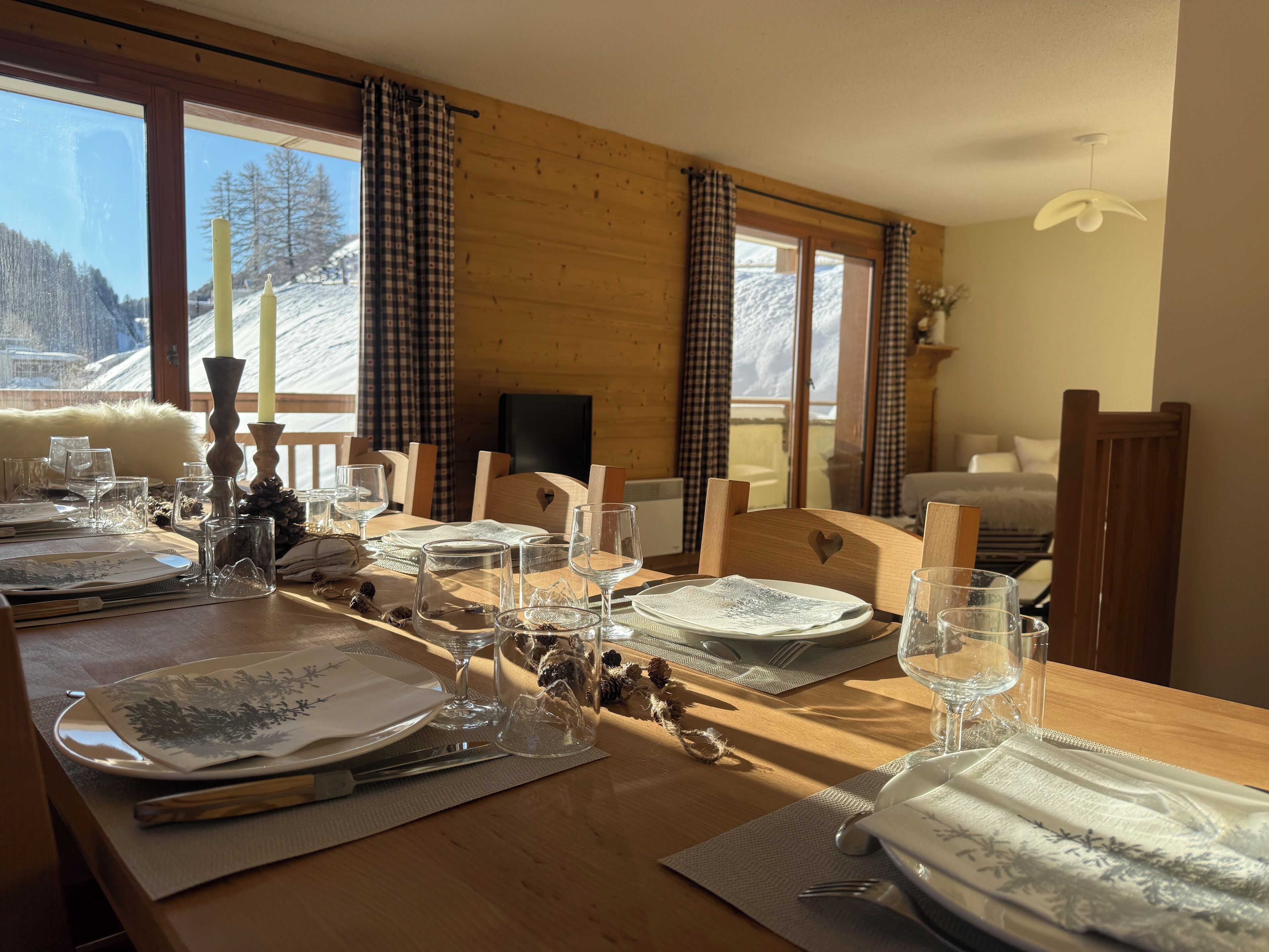 A dining table set for four with a view of a snowy mountain landscape through large windows.