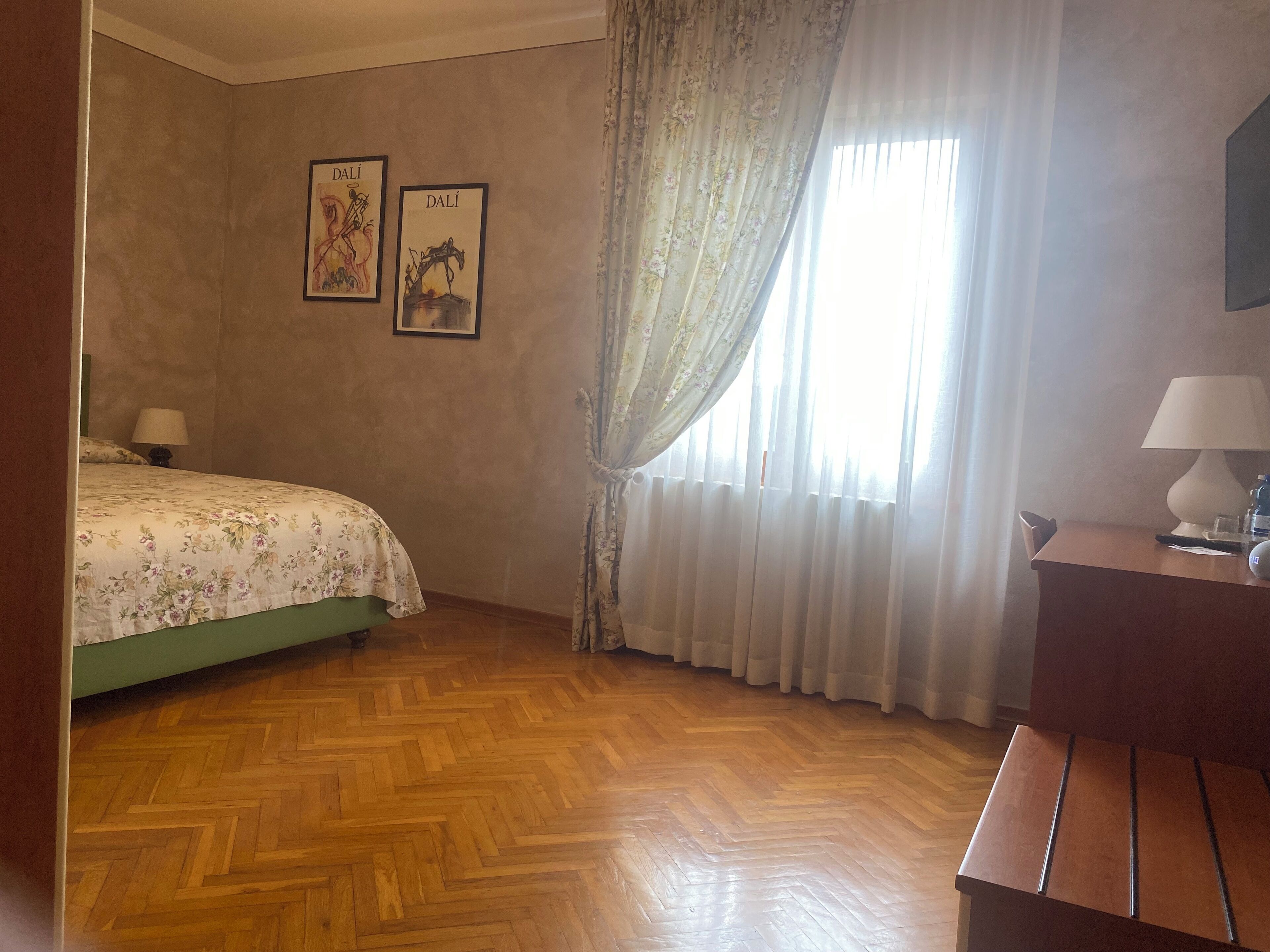 Habitación de hotel con una cama, un escritorio y una ventana con cortinas.