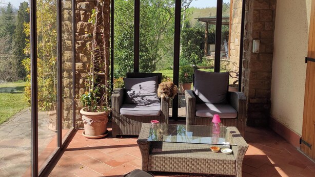 Un patio cubierto con muebles de mimbre, una mesa de vidrio y plantas en macetas.